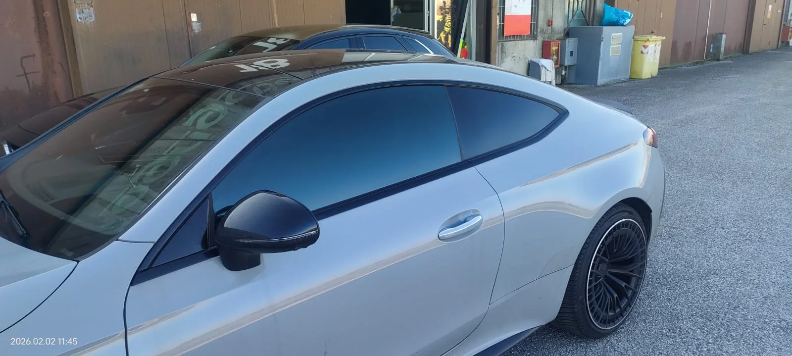 Dettaglio dello specchietto di una coupé celeste con vetri oscurati